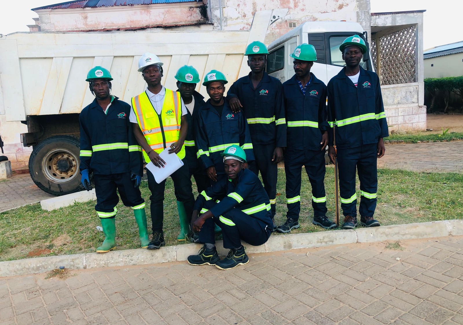 Parte da equipa técnica e operacional da JM Global mobilizada para a obra de pavimentação na Ilha de Moçambique, junto a um dos veículos utilizados no transporte de material.